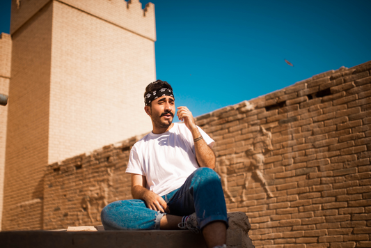 Un homme qui porte un bandana avec un jean et un t-shirt blanc