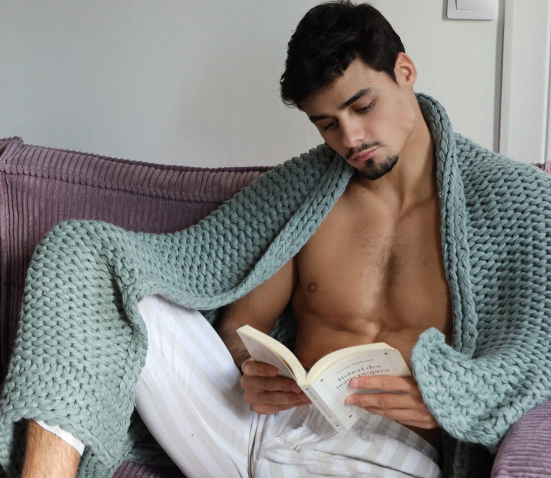 Homme avec un plaid de la marque Monsieur Charli sur les épaules lisant un livre