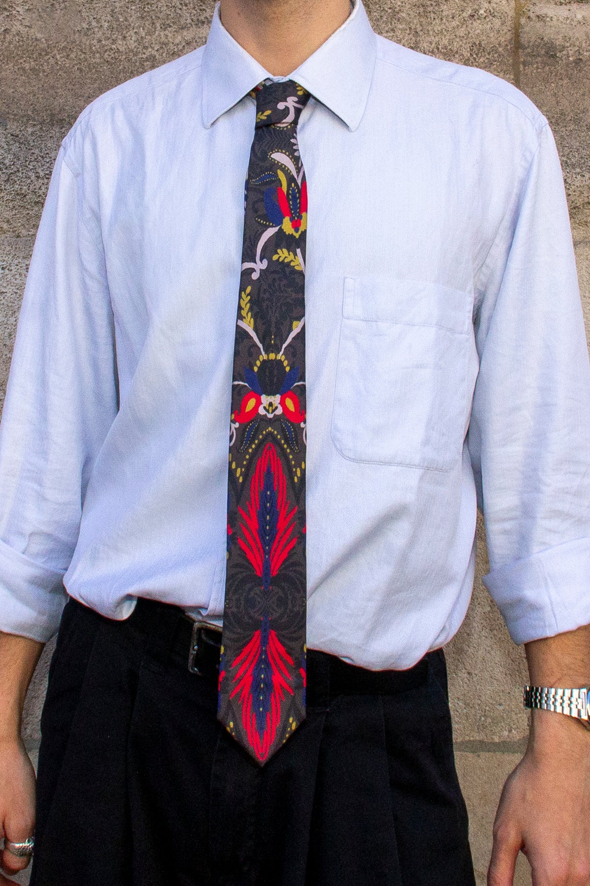 Gros plan sur la cravate NIELS à motifs botaniques multicolores portée avec une chemise bleu clair.