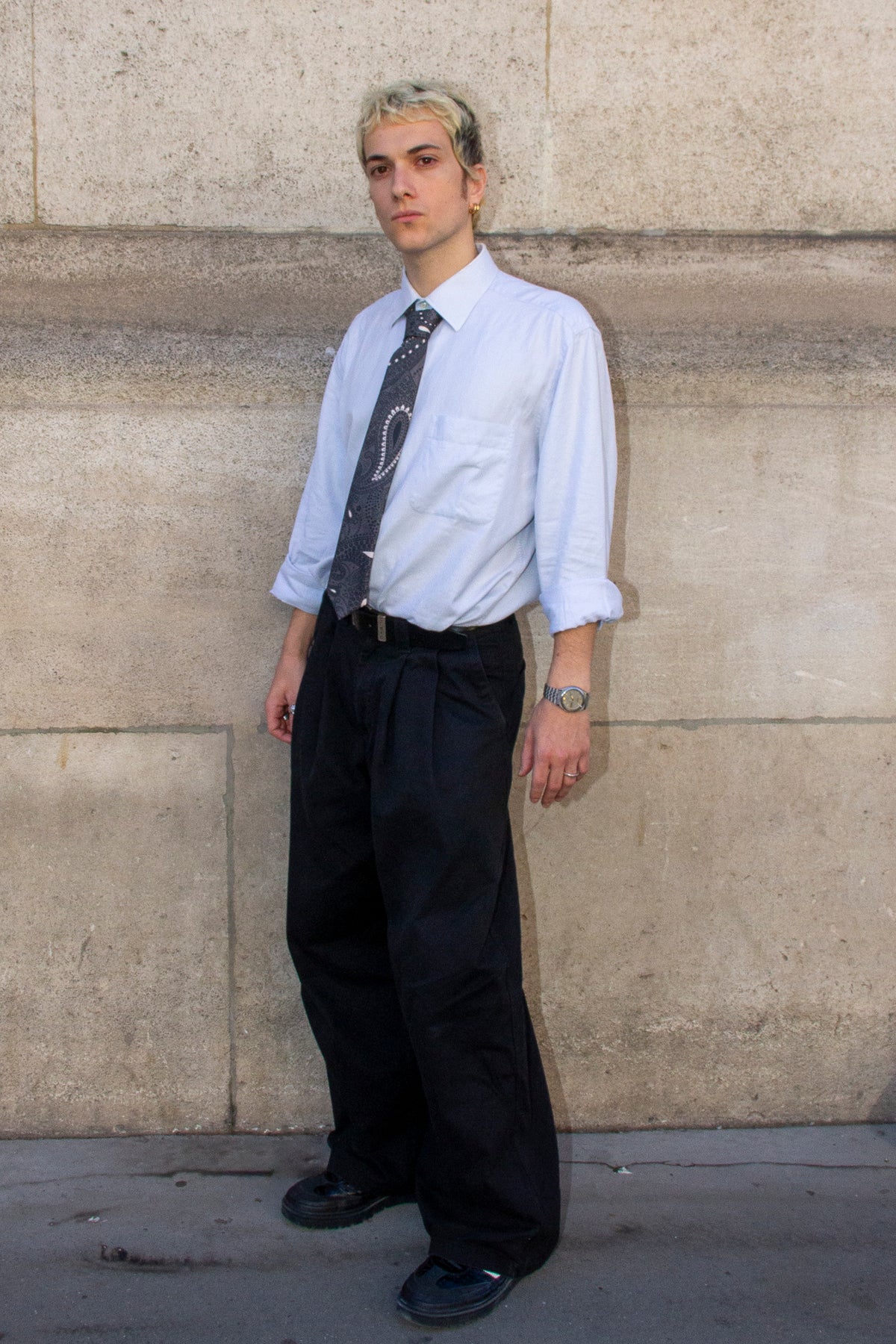 Homme de trois quarts portant une cravate à motifs paisley gris ardoise avec une chemise bleu clair.