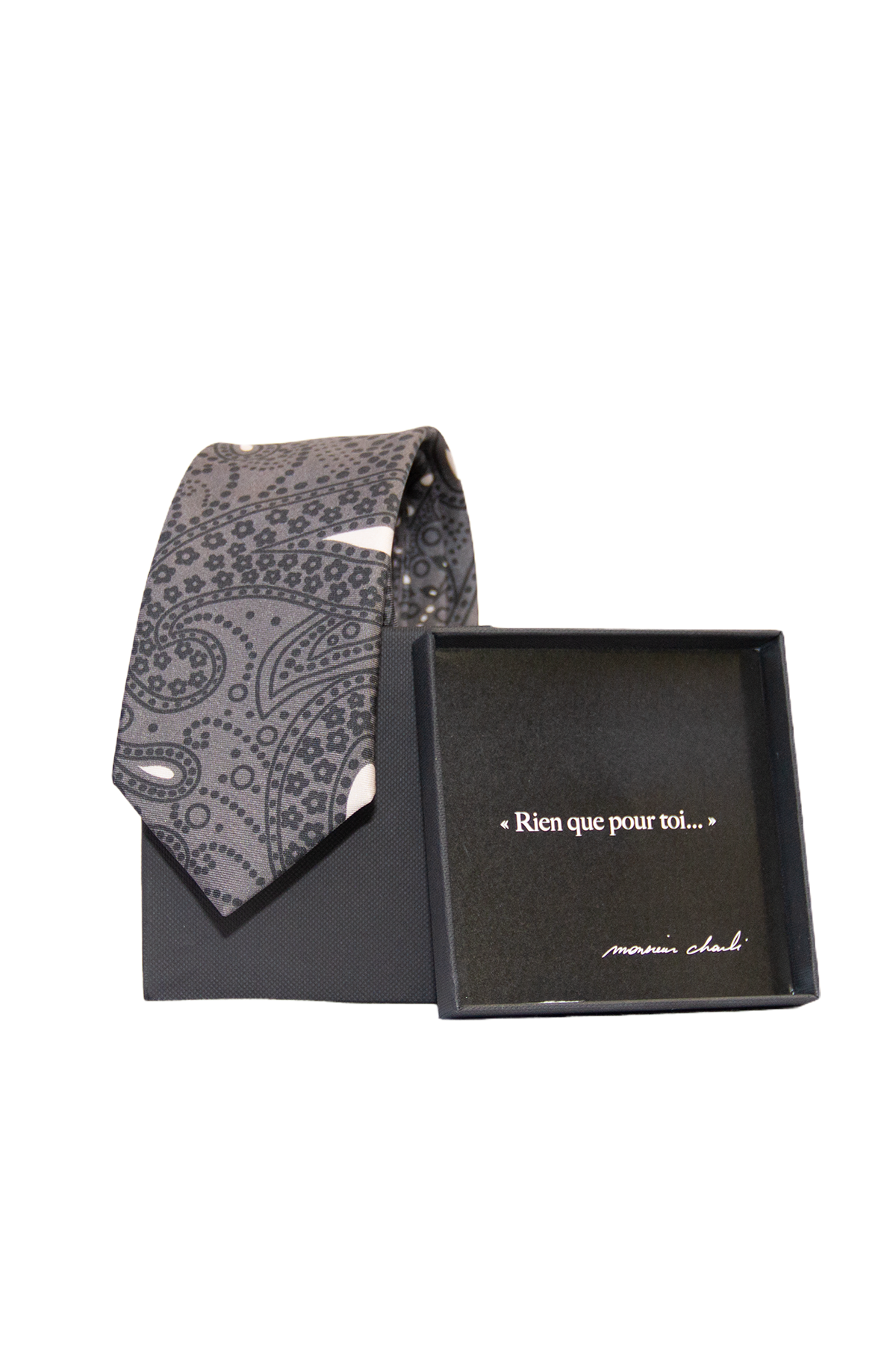Cravate en soie à motifs paisley gris ardoise présentée avec son coffret cadeau noir Monsieur Charli ouvert.