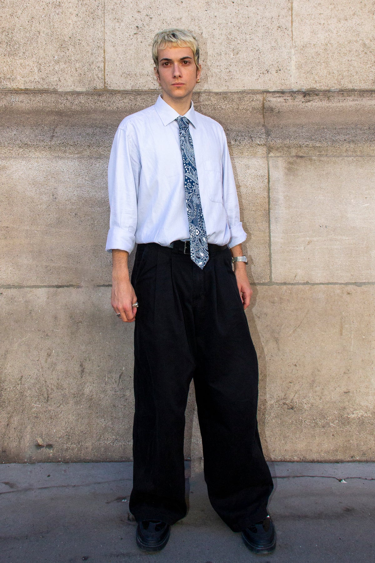 Un homme dans la rue avec une cravate en soie et un pantalon noir.
