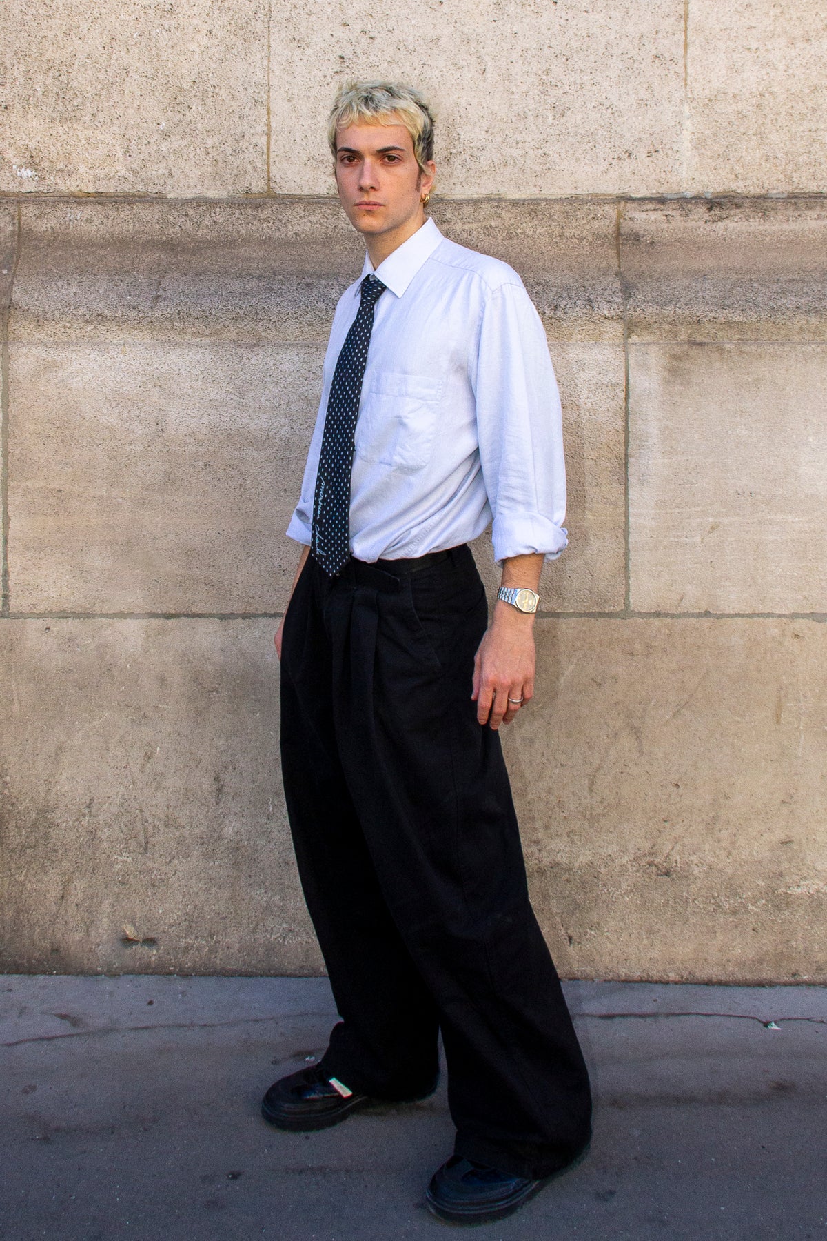 Homme de trois quarts portant une cravate noire à petits pois blancs avec une chemise bleu clair.