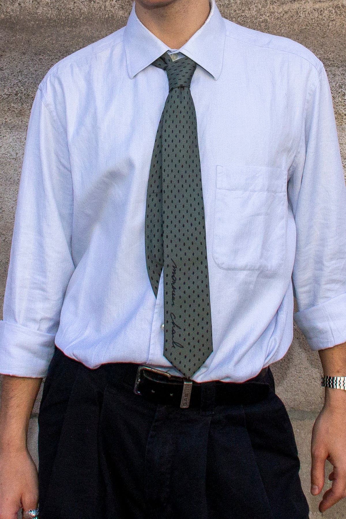 la cravate académie olive à pois noir porté sur une chemise bleu clair.