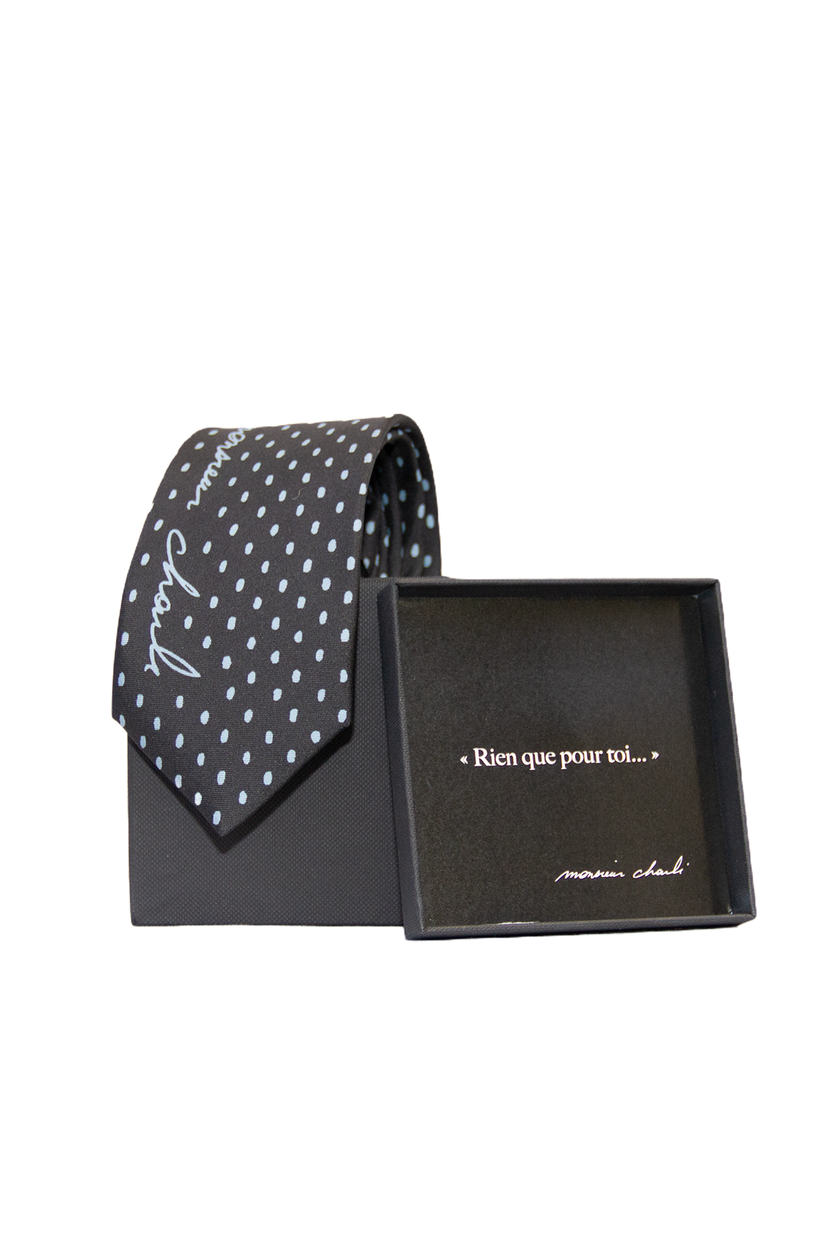 Cravate en soie noire à petits pois blancs présentée avec son coffret cadeau noir Monsieur Charli ouvert.