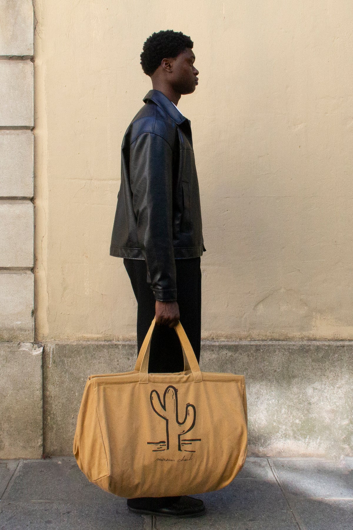 Un homme de profil qui porte le maxi cabas walter camel